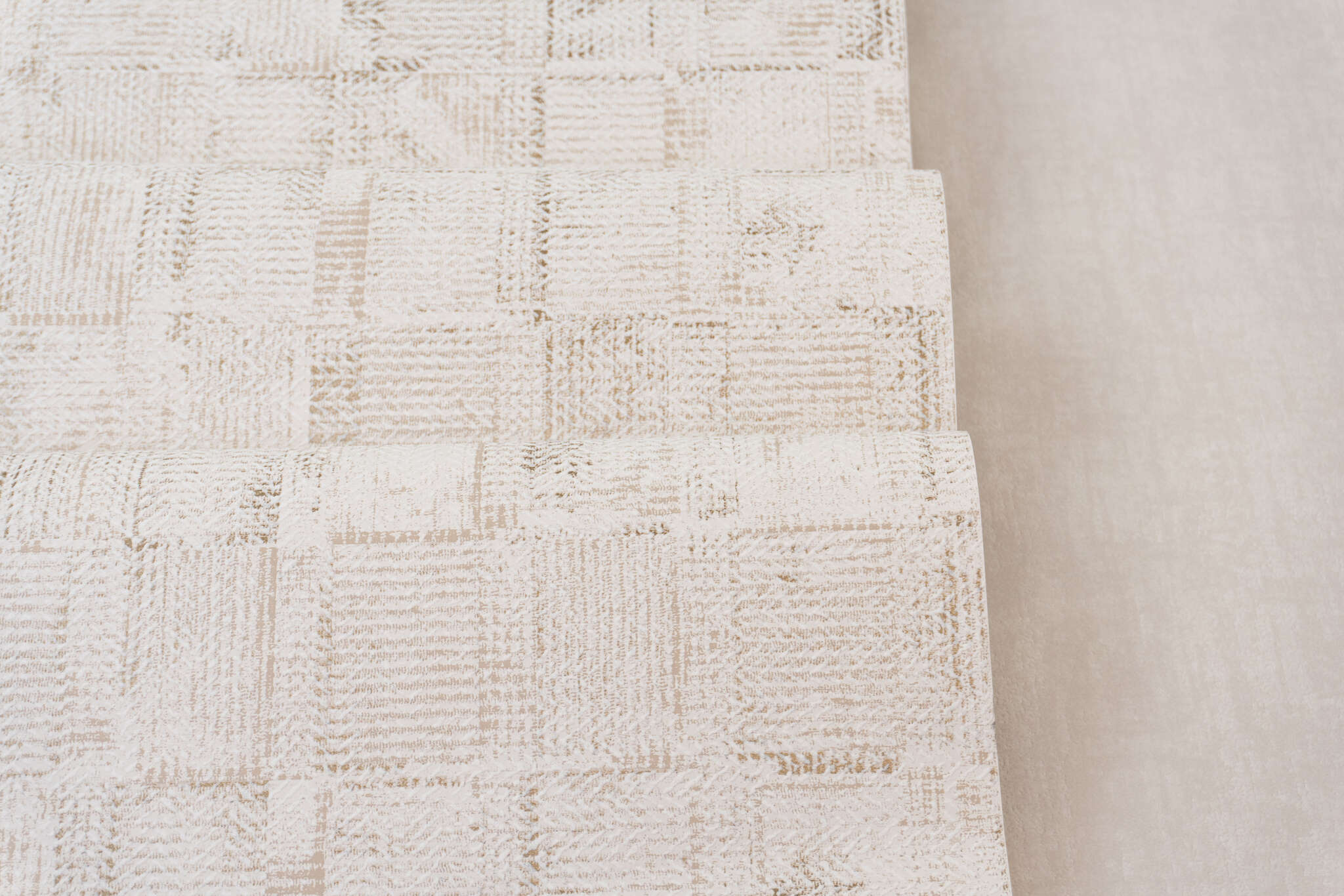 10-314717 Detailaufnahmen 1 Detailed image of Cream-coloured non-woven wallpaper with a woven patchwork texture and a slightly raised look.